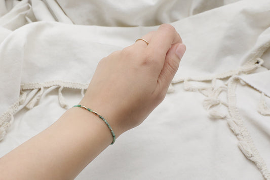 Female writs wearing a dainty Emerald bracelet with Gold Filled details.
