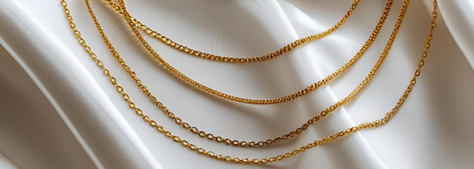 Delicate golden necklaces against a white silk background