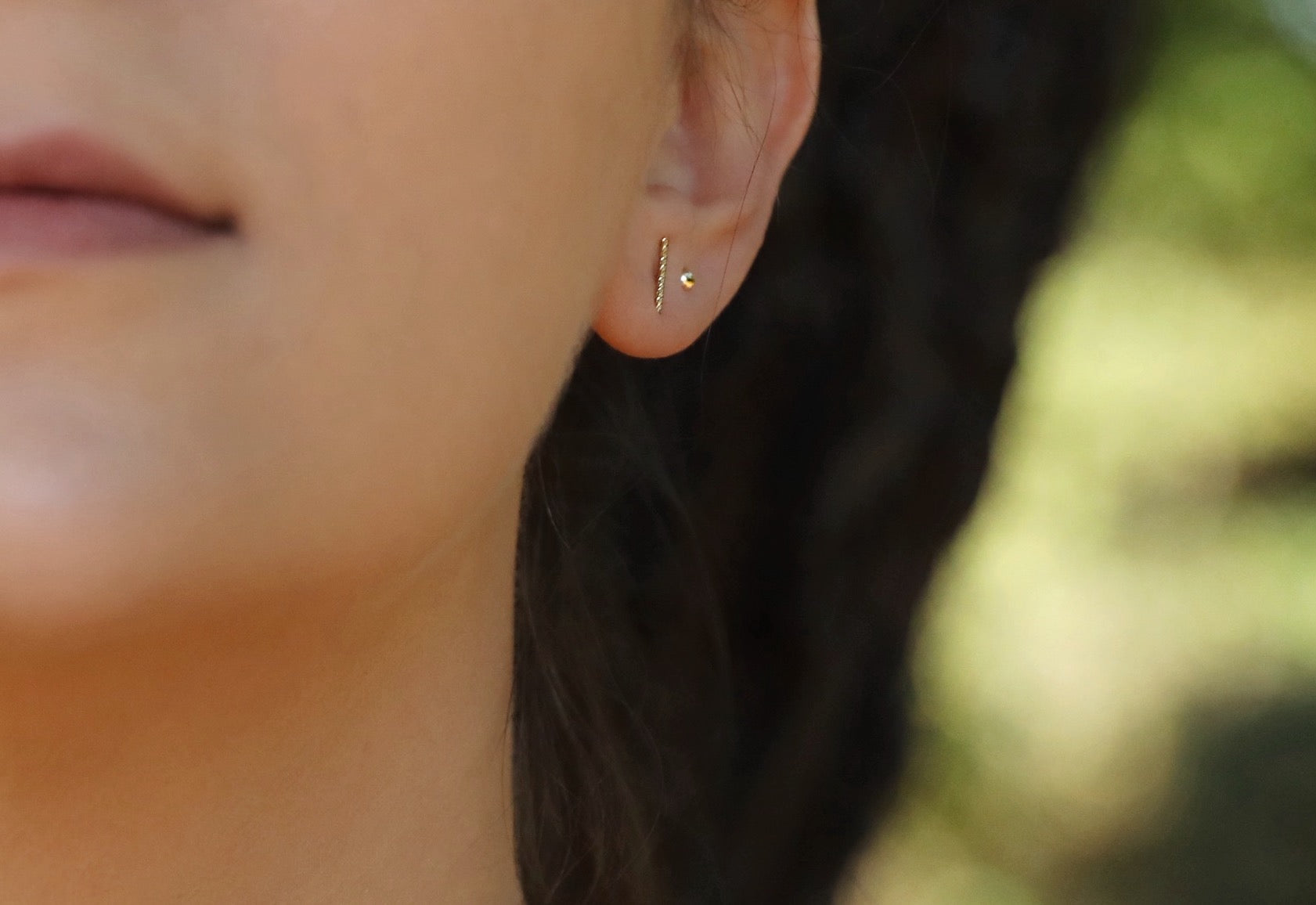 A model wearing The Bark Stud earrings by Gaia's Heirlooms, made of 14k Gold Filled.
