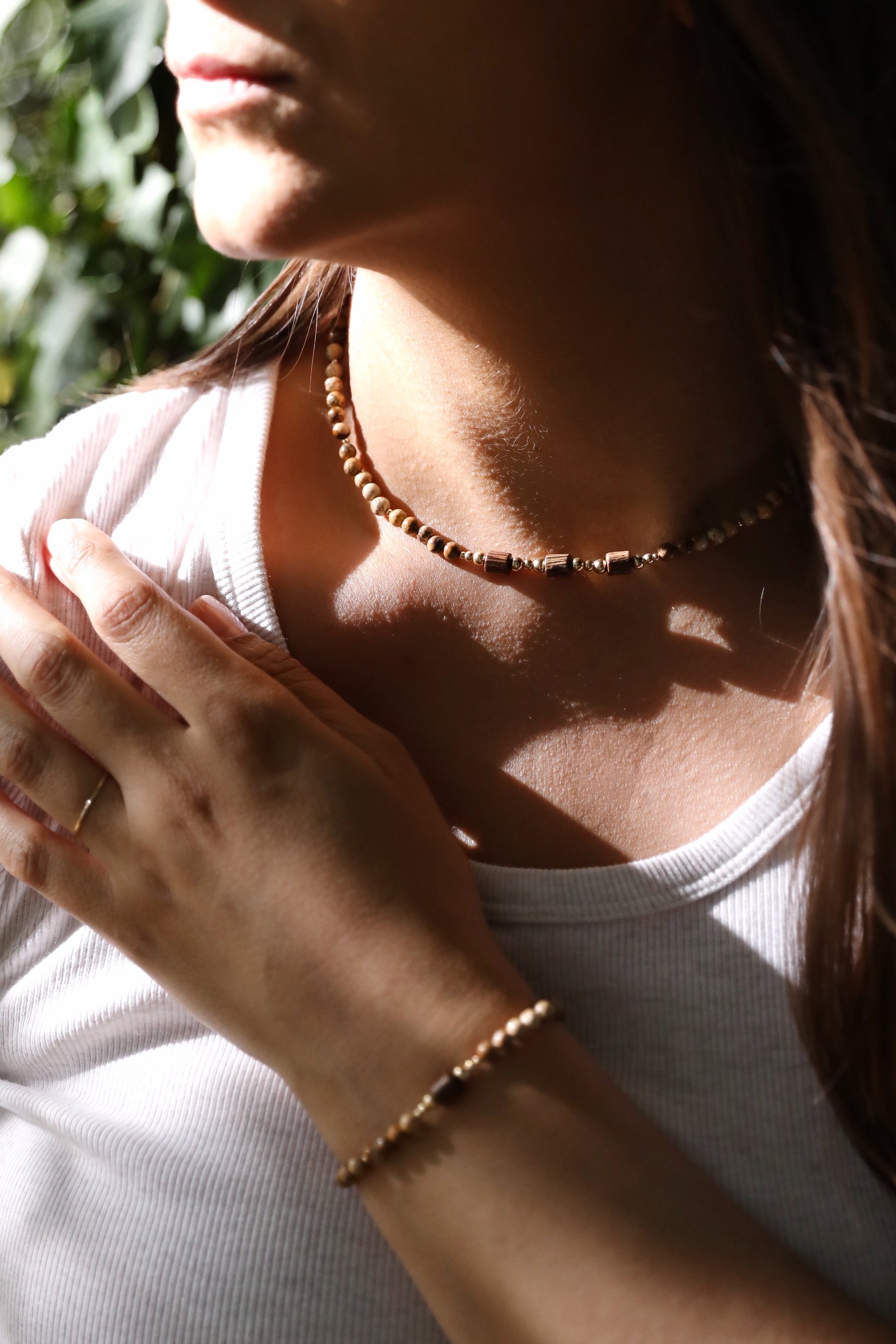 A model wearing The Earth's Story Necklace by Gaia's Heirlooms, made with Picture Jasper beads, natural wood and Gold Filled details.