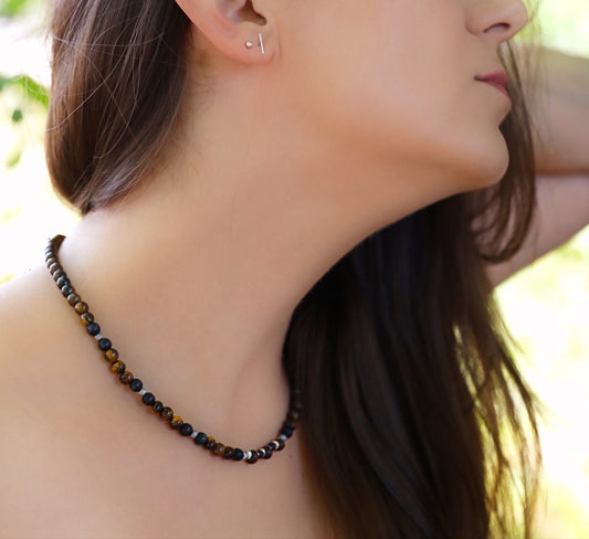 A model wearing The Fierce Wisdom Necklace and Bracelet by Gaia's Heirlooms, made with Tiger's Eye, matte Black Onyx, natural wood and oxidised Sterling Silver beads.