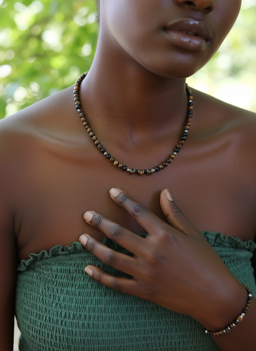 A model wearing The Fierce Wisdom Necklace and Bracelet by Gaia's Heirlooms, made with Tiger's Eye, matte Black Onyx, natural wood and oxidised Sterling Silver beads.