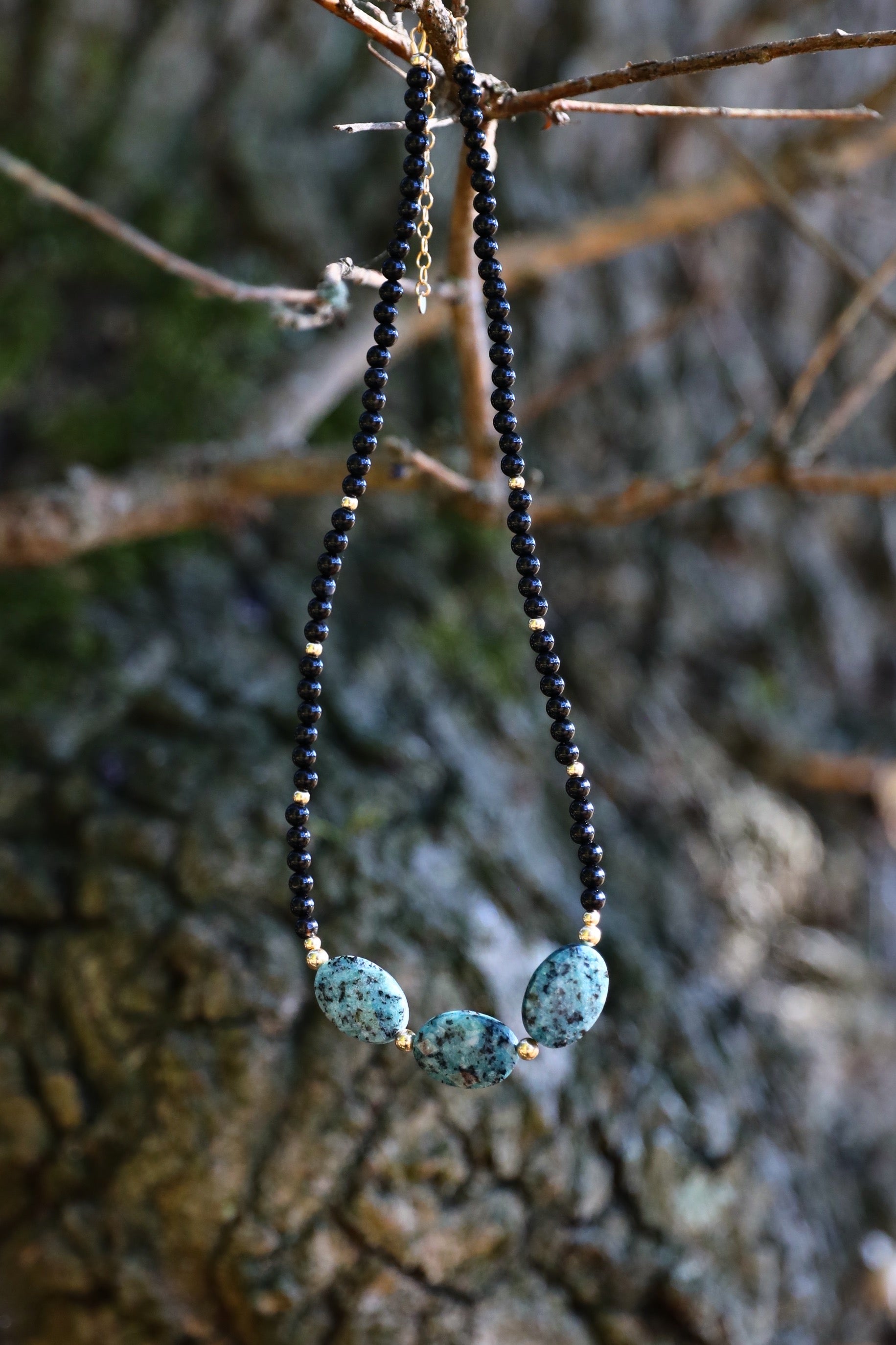The Fortifying Foundations Necklace by Gaiai's Heirlooms, made with Black Onyx beads, three Blue Spot Jasper stones in the middle and Gold Filled details.