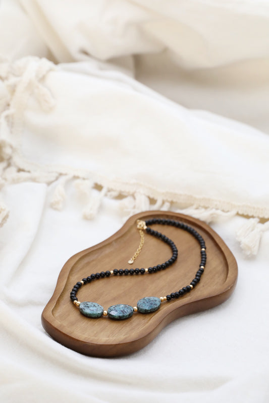 The Fortifying Foundations Necklace by Gaiai's Heirlooms, made with Black Onyx beads, three Blue Spot Jasper stones in the middle and Gold Filled details.