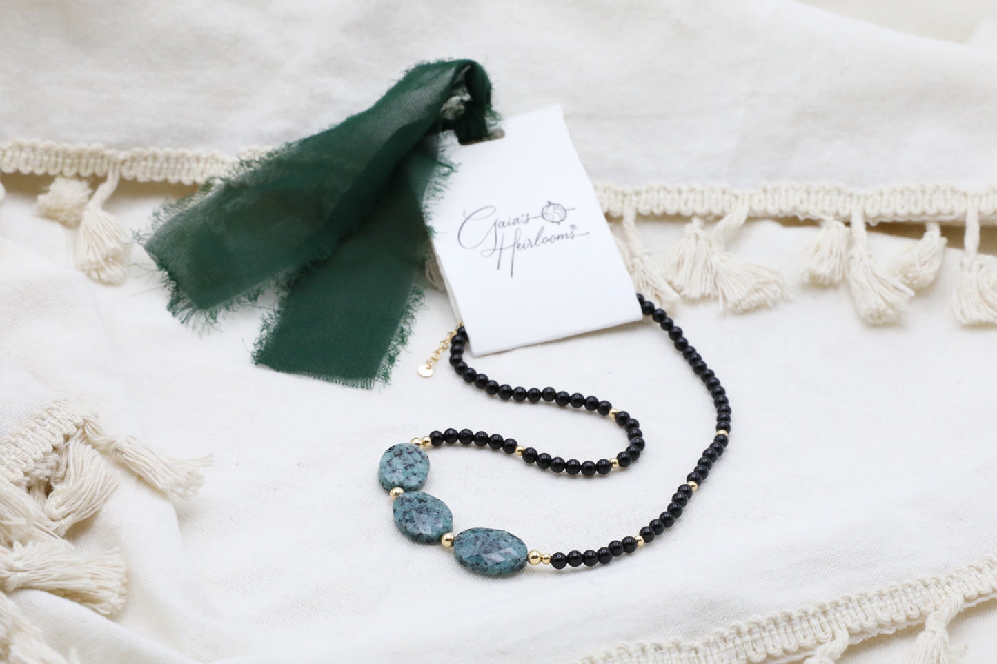 The Fortifying Foundations Necklace by Gaiai's Heirlooms, made with Black Onyx beads, three Blue Spot Jasper stones in the middle and Gold Filled details.