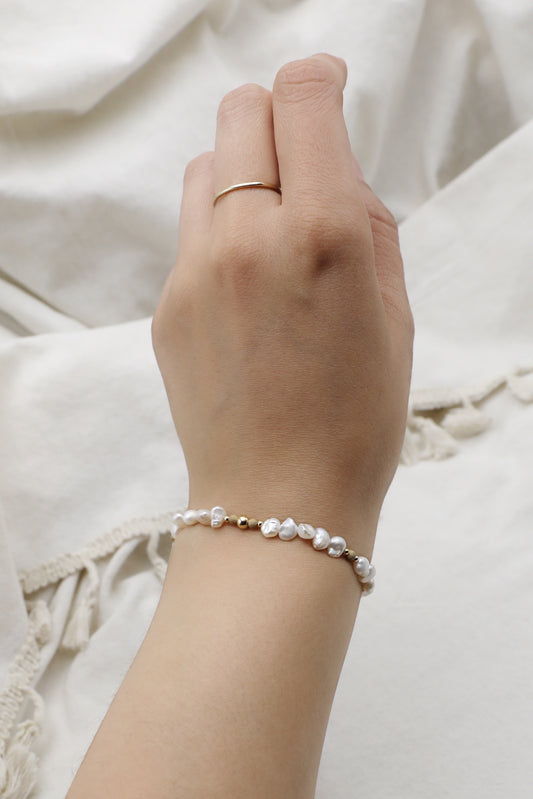 Female wrist wearing a Mother of Pearl bracelet with Gold Filled details.