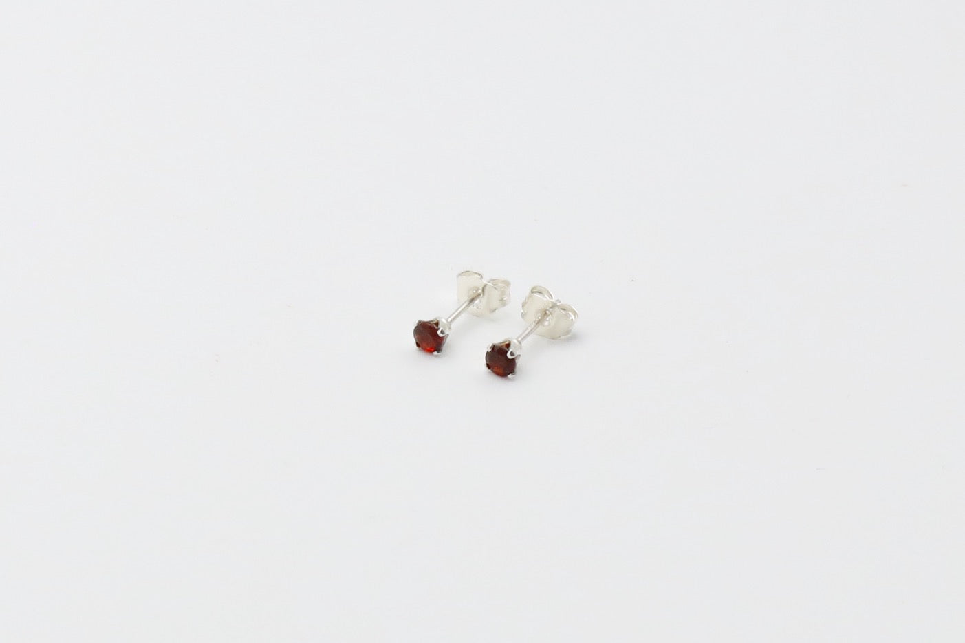 Pair of dainty Garnet stud earrings in Sterling Silver. Size: 3mm