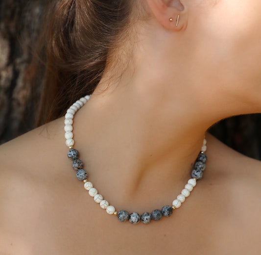 A model wearing The Inner Fire Necklace by Gaia's Heirlooms, made with Howlite and Flame Stone large beads, finished with Gold Filled details.