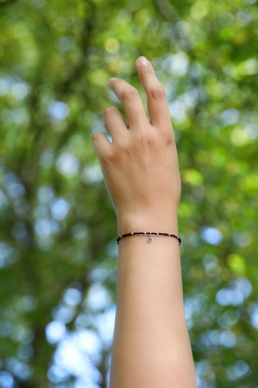 Detail of a model's wrist wearing The Radiant Guardian Bracelet by Gaia's Heirlooms, made with tiny Black Spinel beads and Sterling Silver.