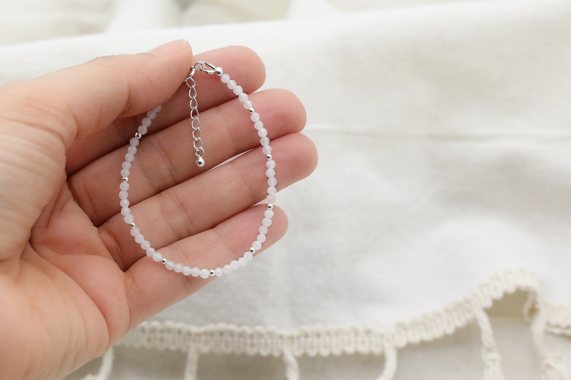 Female hand holding a White Jade Bracelet in Sterling Silver.