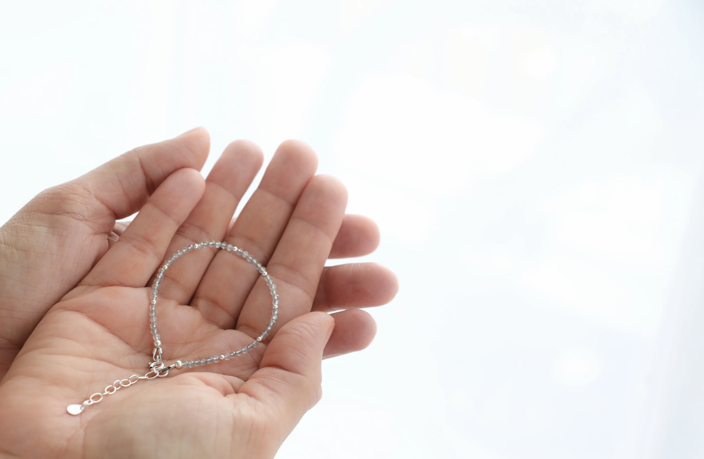 Pair of female hands holding a Labradorite dainty Bracelet in Sterling Silver